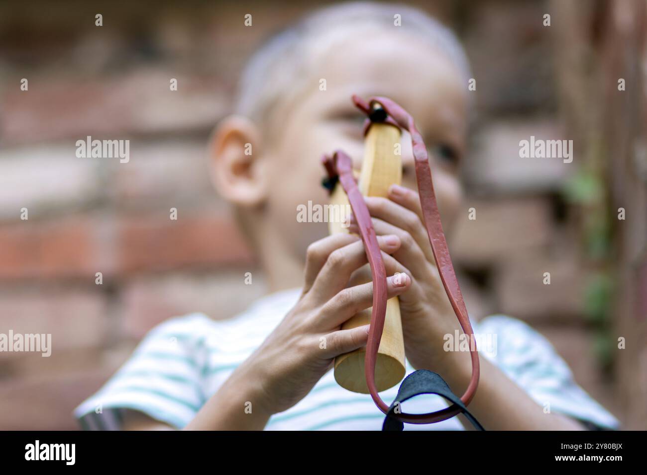 Un bambino gioca con una fionda per strada Foto Stock