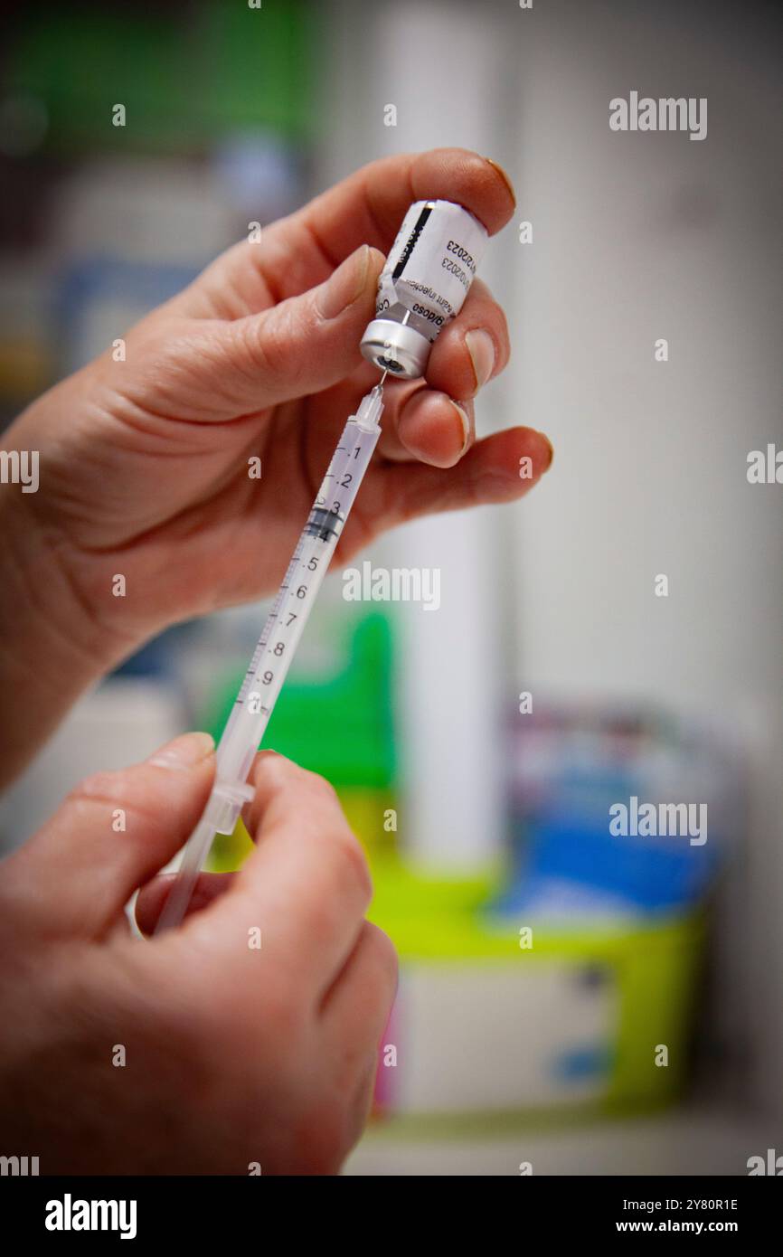 Vaccinazione contro Covid-19 in farmacia: Un farmacista prepara dosi di influenza stagionale e vaccini covid19 per il giorno, una fiala di Comirnaty mRNA vac Foto Stock