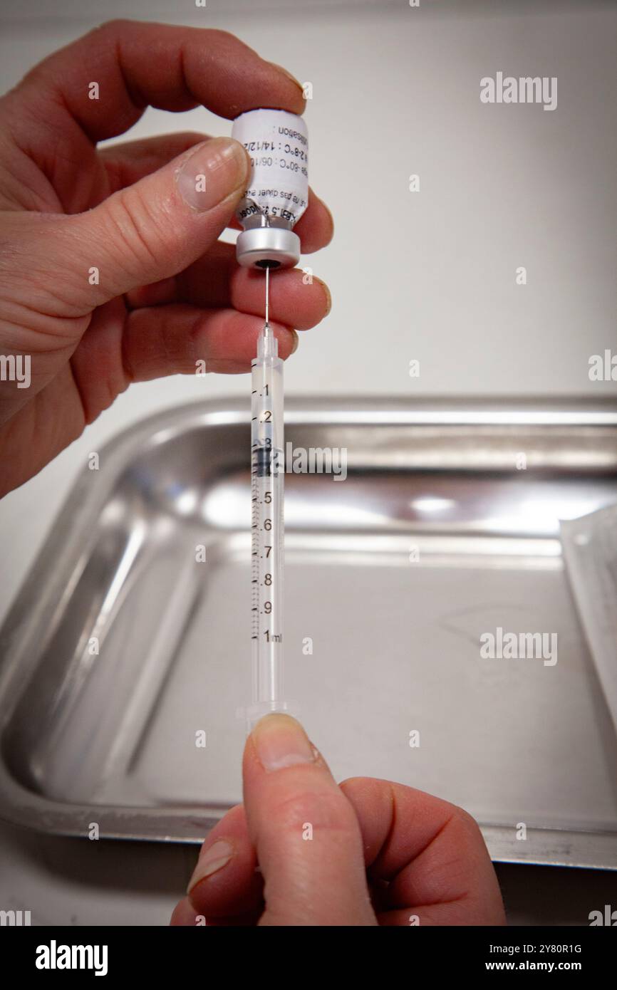 Vaccinazione contro Covid-19 in farmacia: Un farmacista prepara dosi di influenza stagionale e vaccini covid19 per il giorno, una fiala di Comirnaty mRNA vac Foto Stock