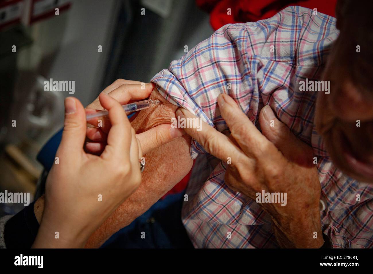 Vaccinazione in farmacia: Un farmacista vaccina una persona anziana contro l'influenza e la covid19. Vaccino antinfluenzale, influenza stagionale Foto Stock