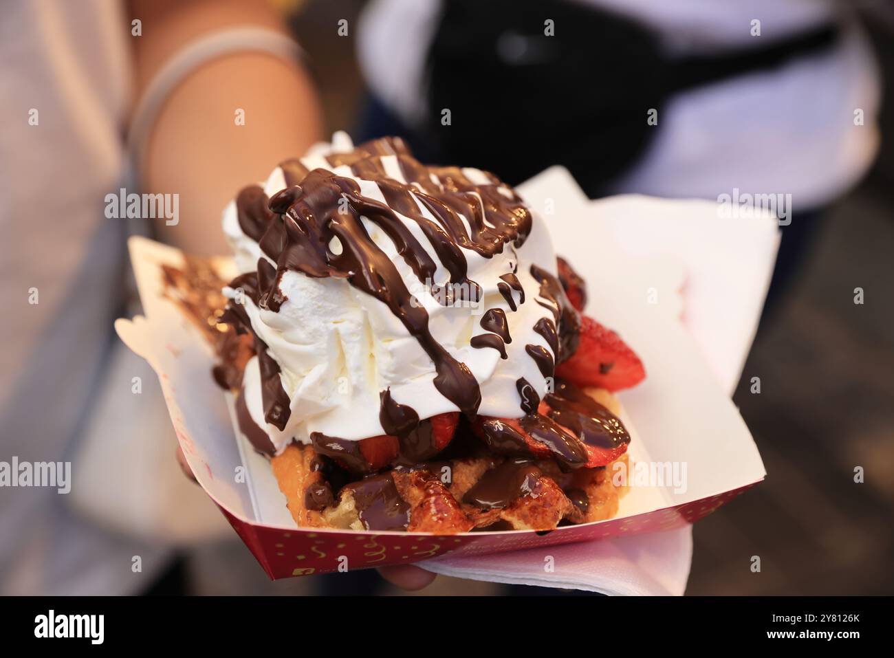 Turista che gusta i tradizionali waffle vicino alla Grand Place di Bruxelles, Belgio. Foto Stock