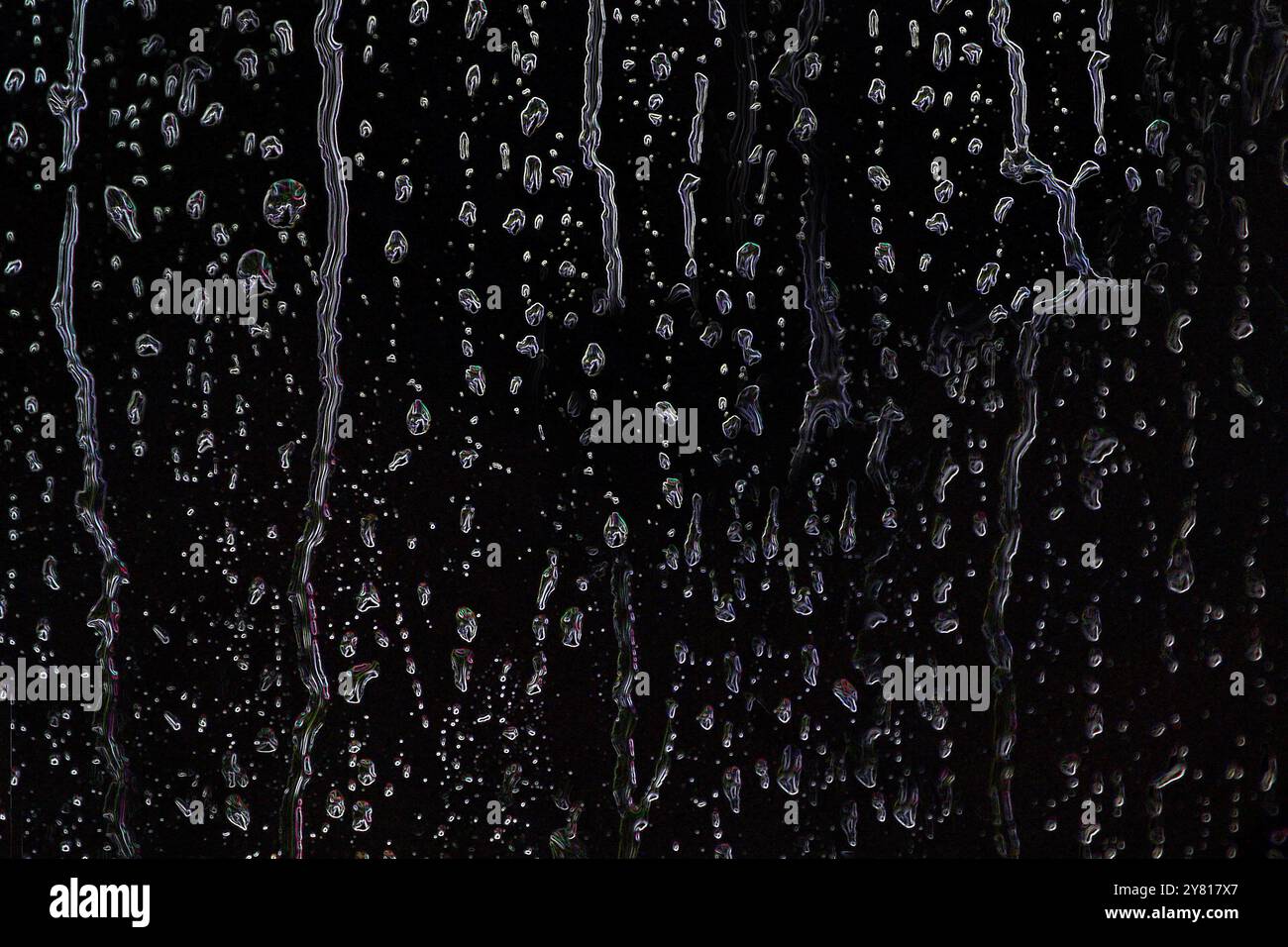 Gocce d'acqua o pioggia si diffondono su uno sfondo nero in primo piano Foto Stock