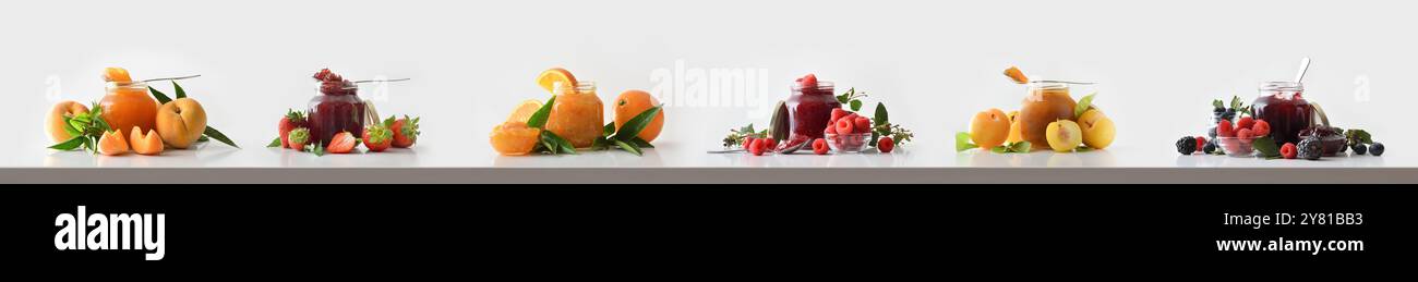 Vasetti di vetro con marmellata di frutta diversa su tavola bianca e sfondo isolato e frutta intorno. Vista frontale. Foto Stock