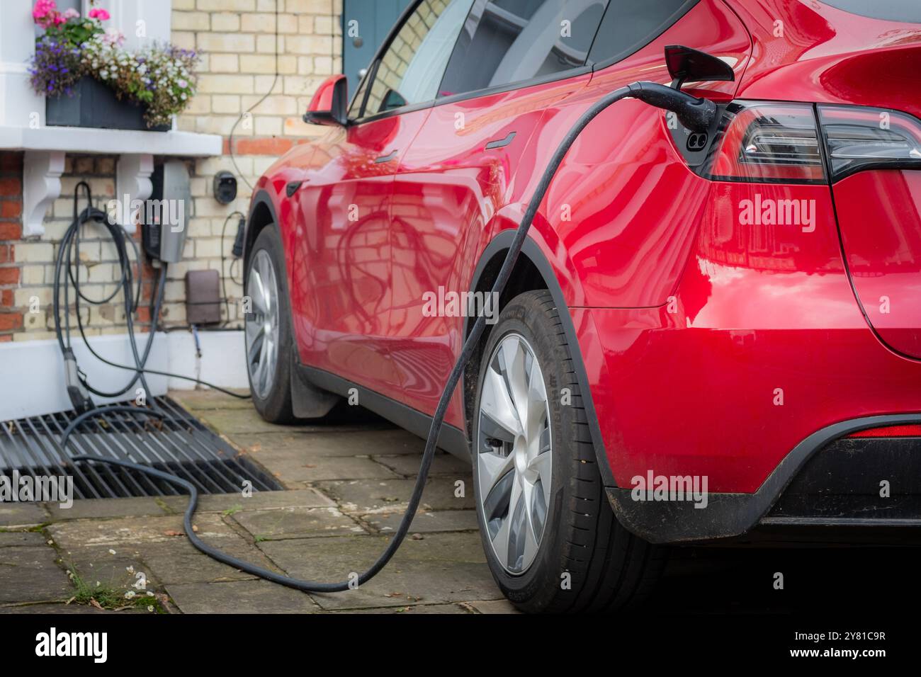 Auto elettrica ricaricata fuori casa in un tipico ambiente residenziale di periferia britannica Foto Stock