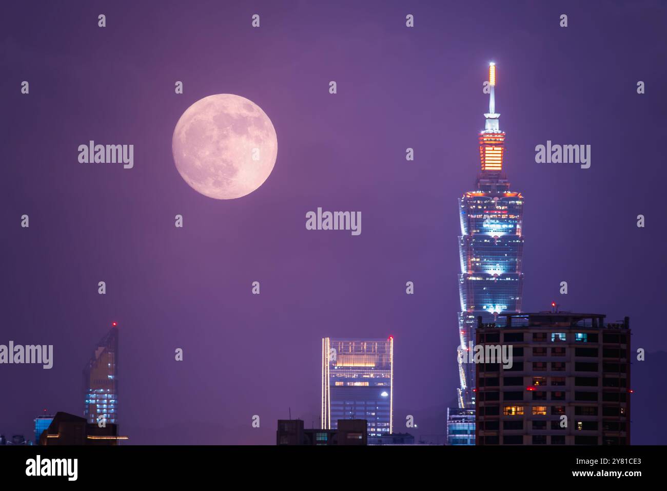 Una luna d'autunno dorata si trova sopra lo skyline di Taipei, che proietta un caldo bagliore sulla città. La scena cattura la tranquillità di una serata d'autunno. Taipei C Foto Stock