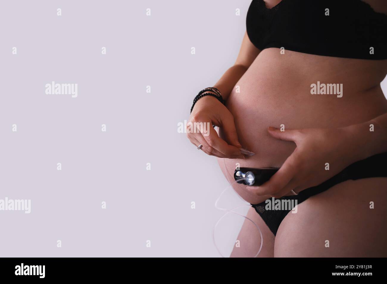 Donna incinta che rimuove il set per infusione dalla pancia mentre tiene in mano la pompa per insulina Foto Stock