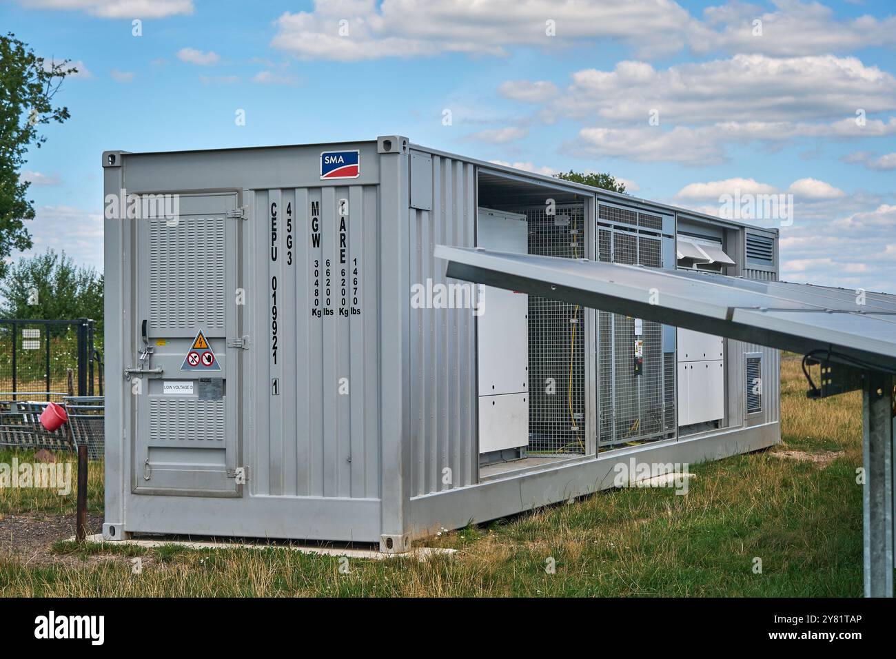 Inverter mobile di energia solare in un'area rurale con alberi e cieli blu. Produzione di energia rinnovabile in armonia con la natura. Foto Stock