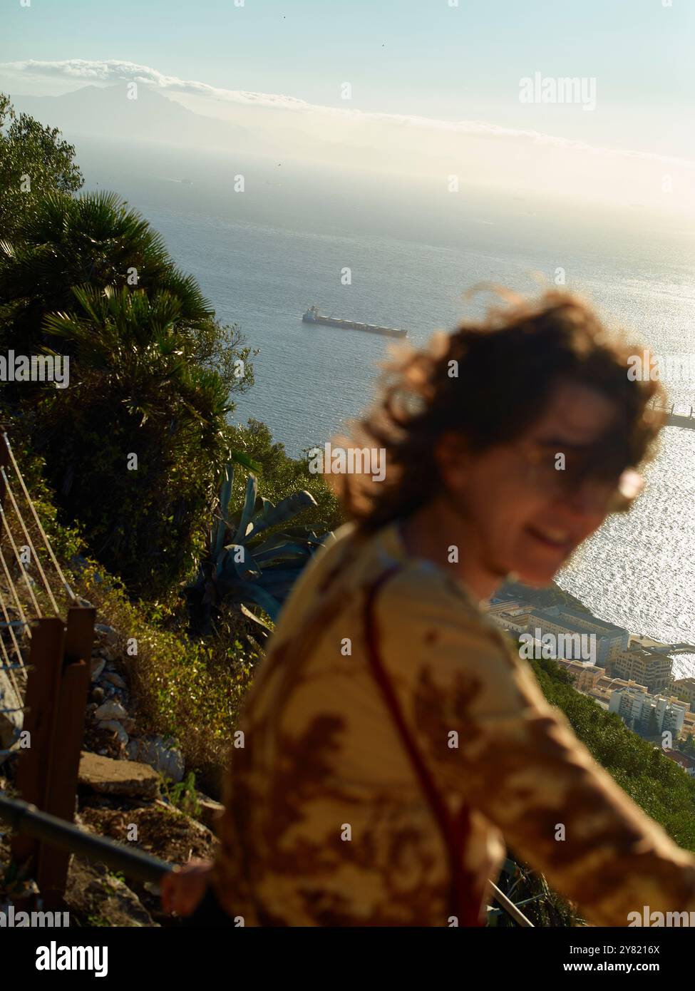 Donna che gode di una vista panoramica sul mare con una nave in lontananza e montagne all'orizzonte. Foto Stock