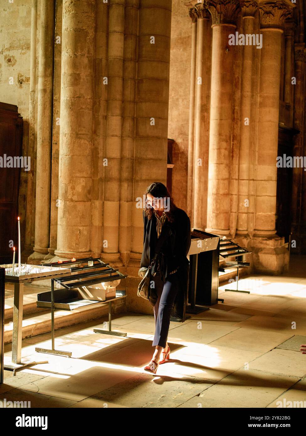 Donna in piedi solennemente in una cattedrale, immersa nella calda luce del sole che filtra attraverso alte finestre. Foto Stock