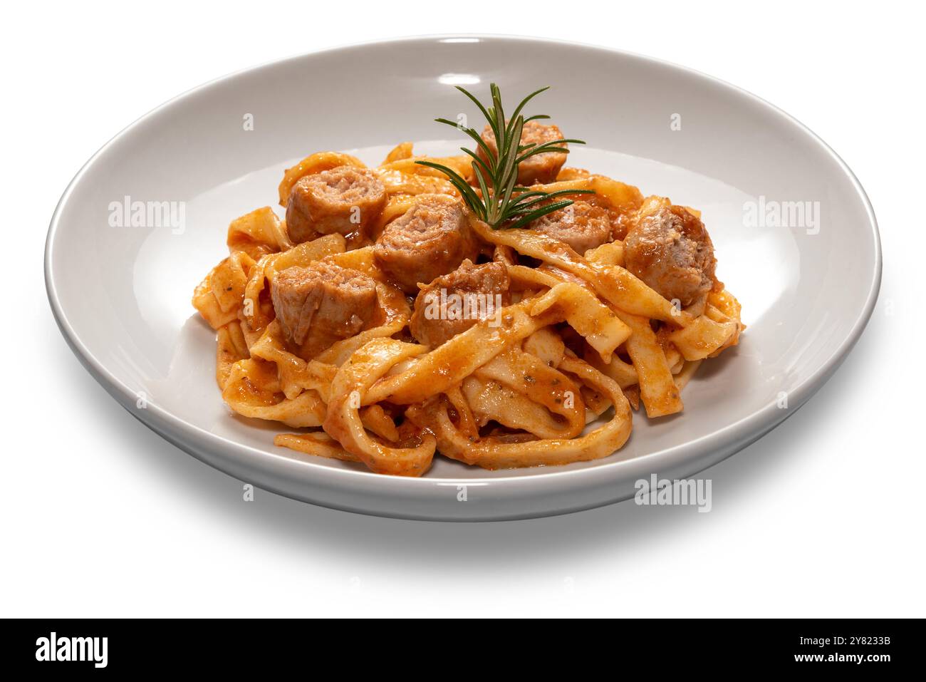 Tagliatelle di pasta all'uovo con salsa di pomodoro rosso con pezzi di salsiccia e rametto di rosmarino in un piatto bianco isolato su bianco Foto Stock