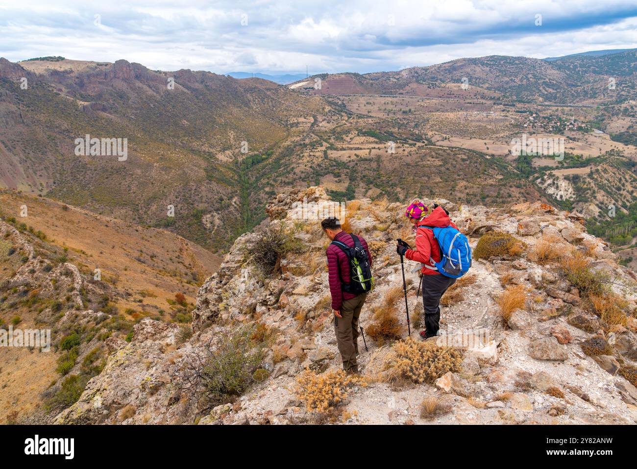 Un paio di escursionisti che camminano con i loro pali e gli zaini su una collina. Foto Stock