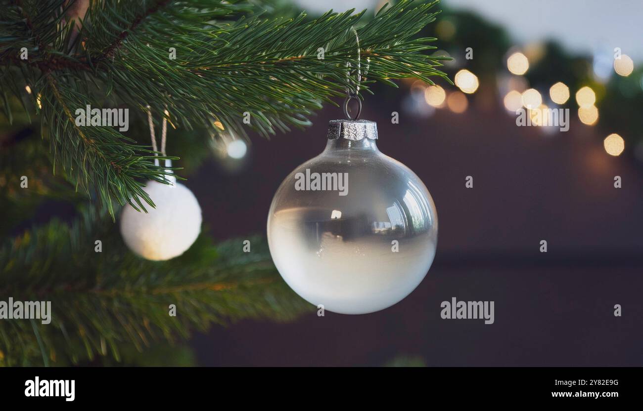 Baule natalizie in vetro appese su rami verdi di pino con luci festive, splendenti ornamenti natalizi con sfondo bokeh, elegante minimalista Foto Stock