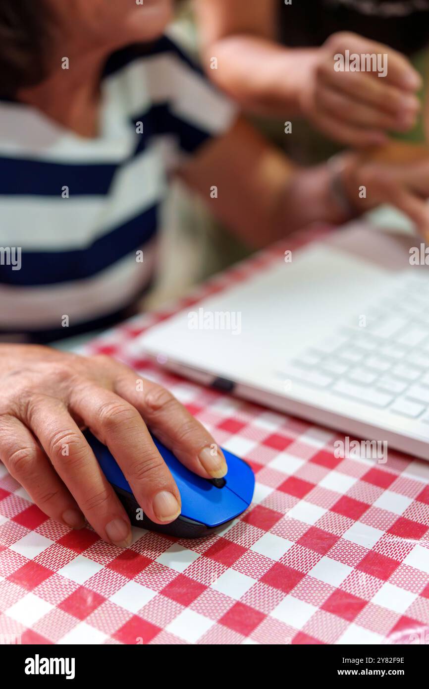 Mano di una donna anziana che usa un notebook per superare il divario digitale Foto Stock
