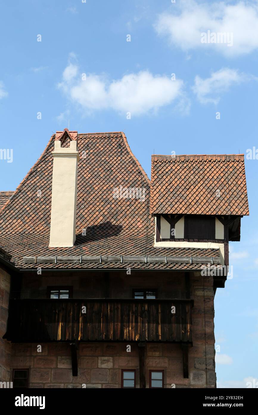 L'intricato design di uno storico edificio di Norimberga mette in evidenza tetti unici e affascinanti dettagli architettonici sotto un cielo luminoso e punteggiato di nuvole. Foto Stock