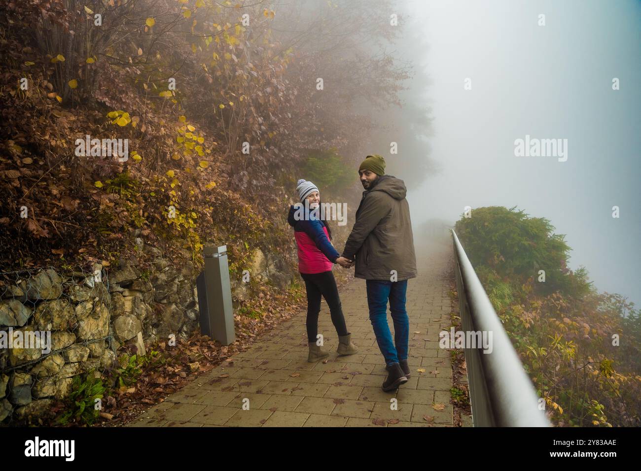 Coppia che cammina sulla strada nebbiosa attraverso i boschi Foto Stock
