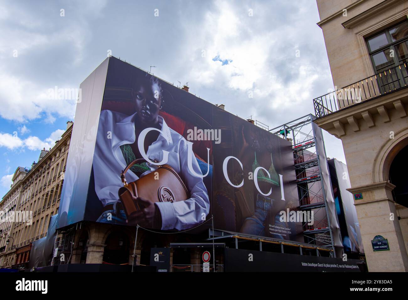 Grande cartellone pubblicitario per Gucci, famoso marchio italiano di lusso, che copre le impalcature dei lavori di restauro sulla facciata di un edificio Foto Stock