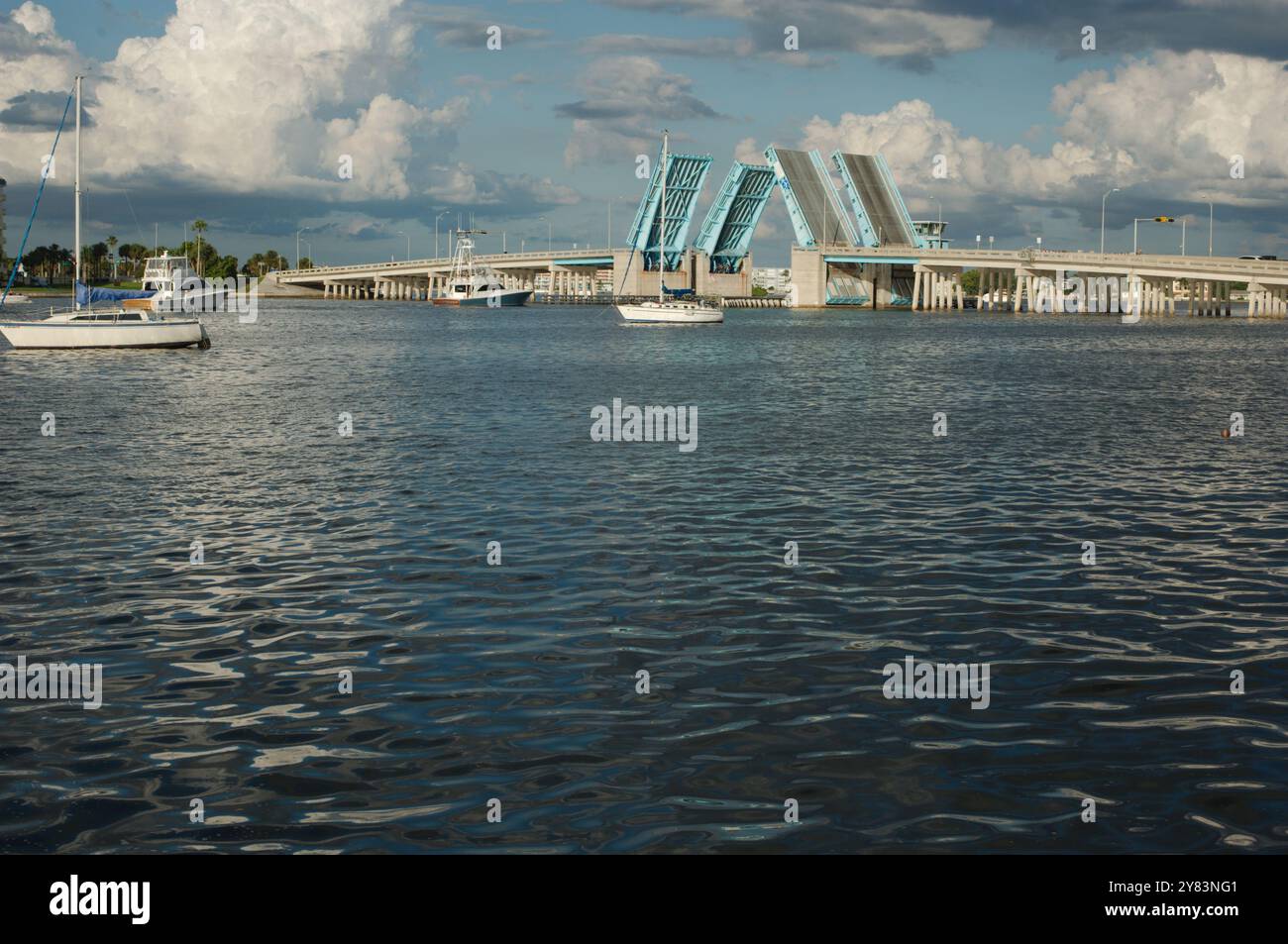 Vista dall'altra parte della costa verso Corey Causeway Drawbridge aperto di colore blu. Due barche a vela al centro e altre barche che si dirigono sotto il ponte. Puffy Foto Stock