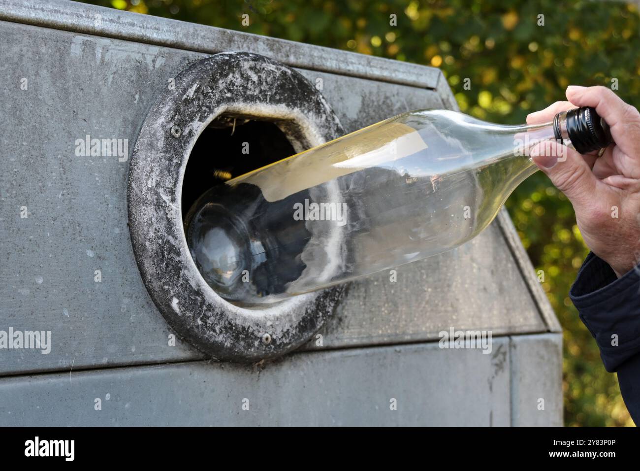 Mano di un uomo che getta una bottiglia in un contenitore di vetro per il riciclaggio delle materie prime, stile di vita sostenibile per la protezione dell'ambiente, spazio di copia, Foto Stock