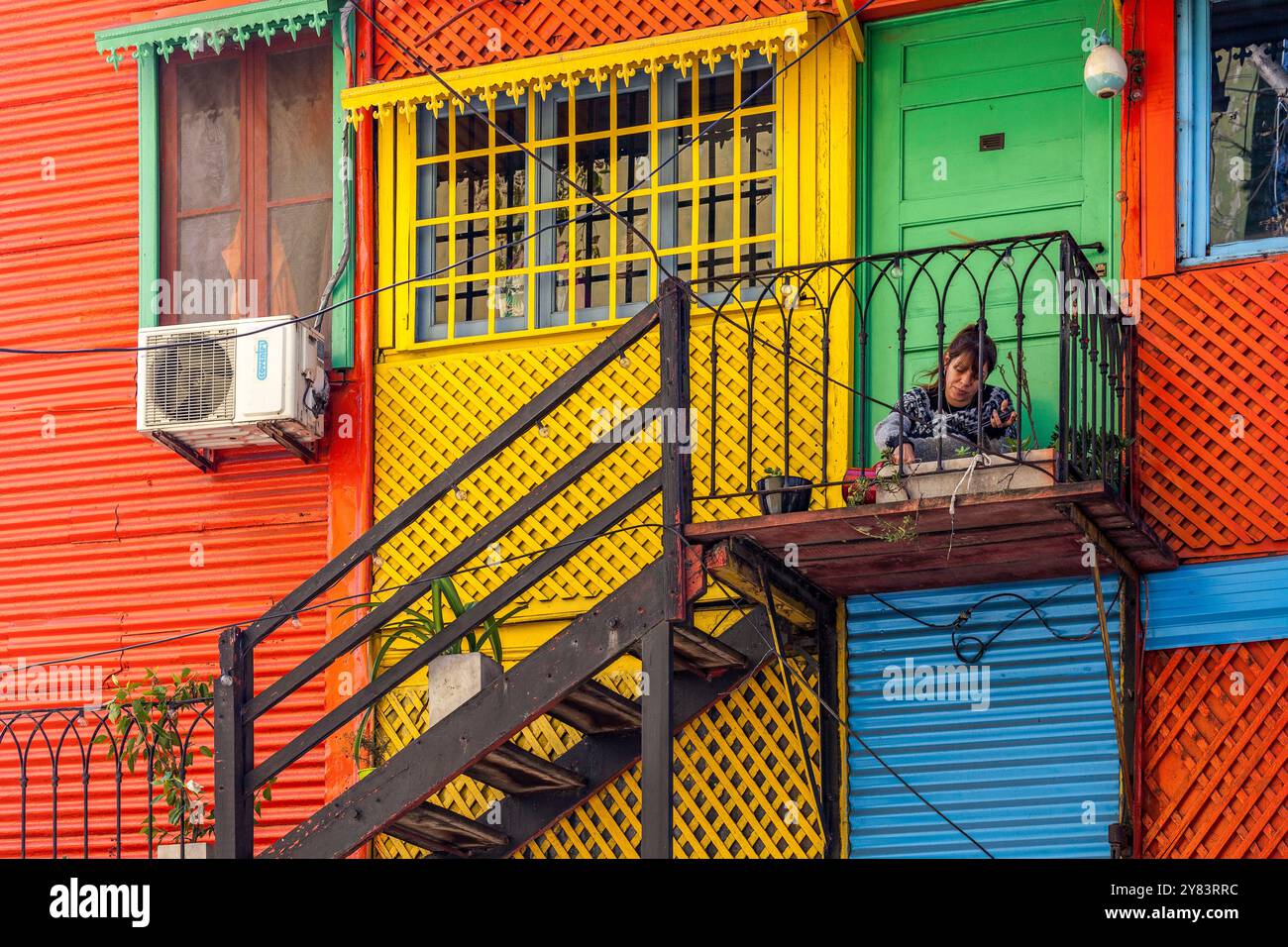 Donna fuori casa tra gli edifici colorati del mercato la Boca a Buenos Aires, Argentina Foto Stock