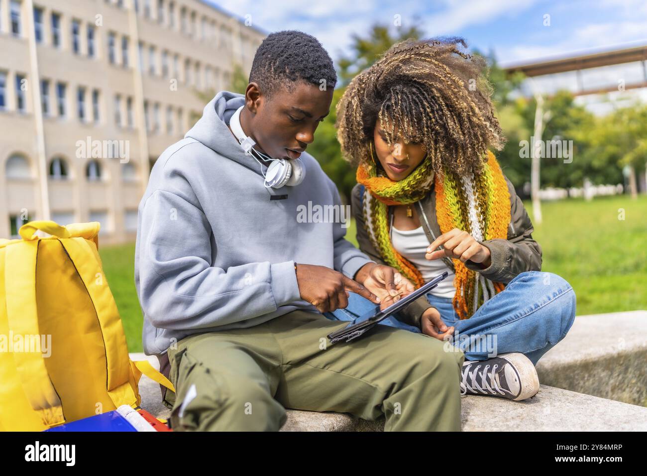 Gli studenti sono dipendenti dalla tecnologia e da Internet seduti fuori dal campus utilizzando un tablet digitale Foto Stock