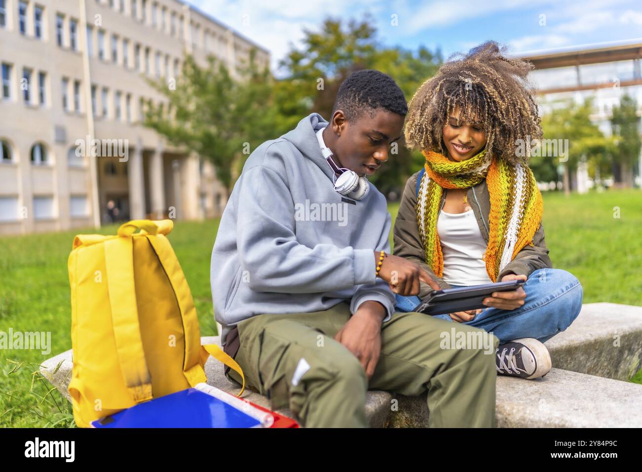 Due studenti universitari di sesso maschile e femminile che utilizzano un tablet digitale fuori dal campus Foto Stock