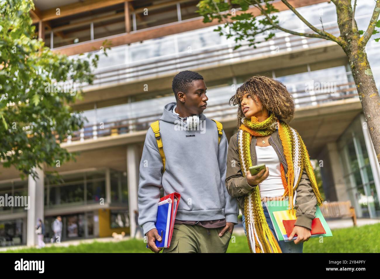 Studenti multietnici che escono dal campus universitario in una giornata di sole d'autunno Foto Stock