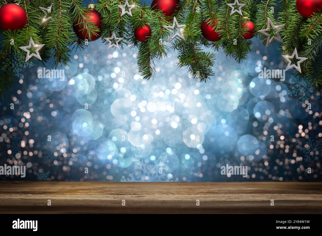 Sfondo astratto per Natale, con un tavolo in legno e rami di abete verdi appesi decorati con baule e stelle che incorniciano uno sfondo astratto Foto Stock