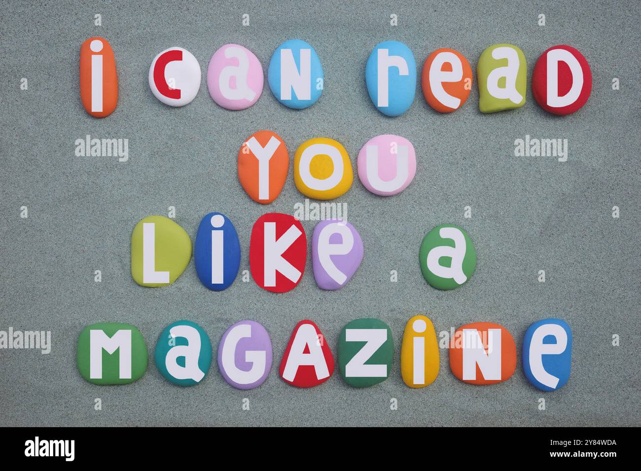 Posso leggervi come una rivista, messaggio creativo composto da lettere di pietra multicolore dipinte a mano su sabbia verde Foto Stock