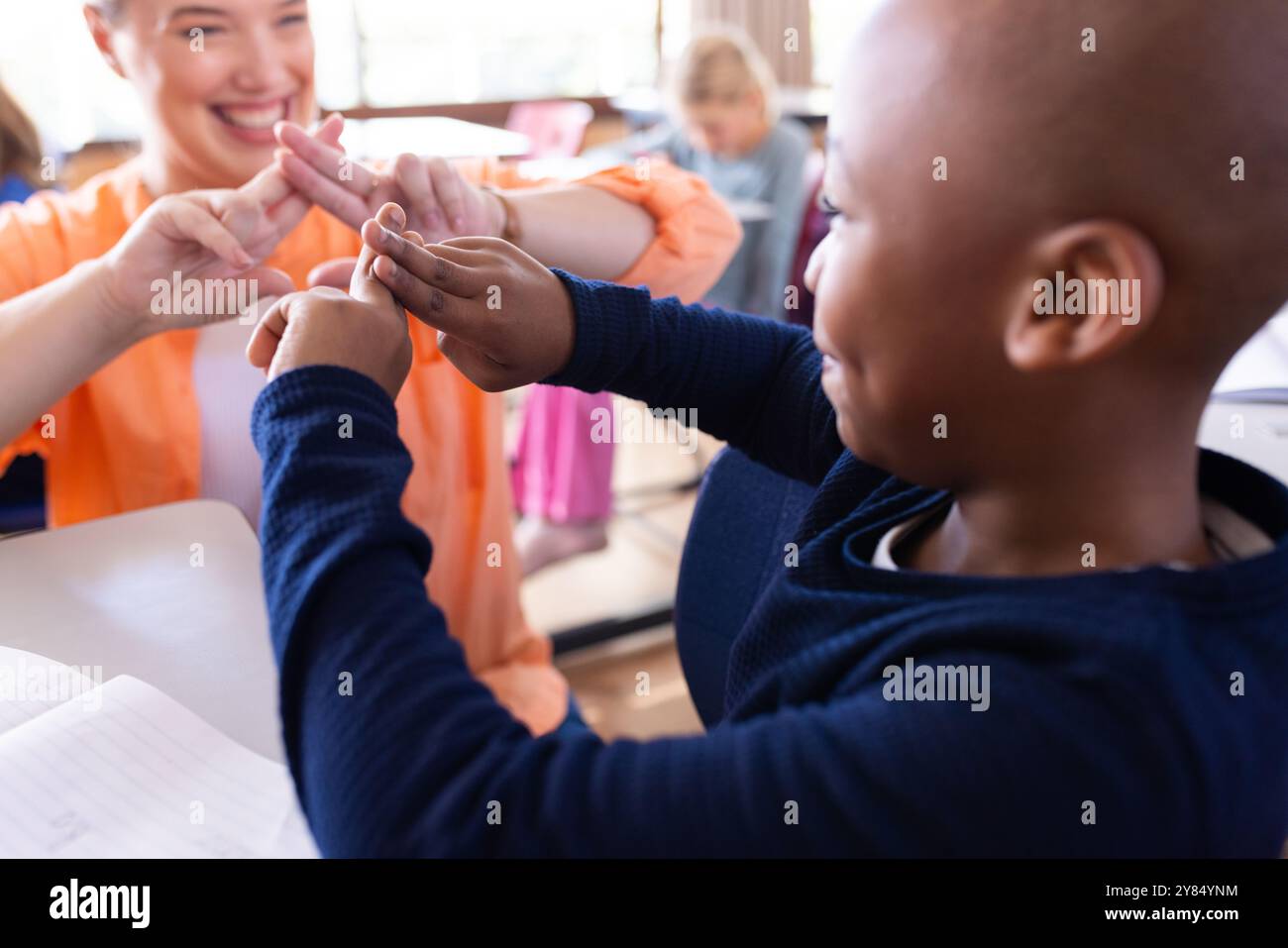 A scuola, insegnante donna e ragazzo afroamericano che gioca il linguaggio dei segni, sorridendo e divertendosi Foto Stock