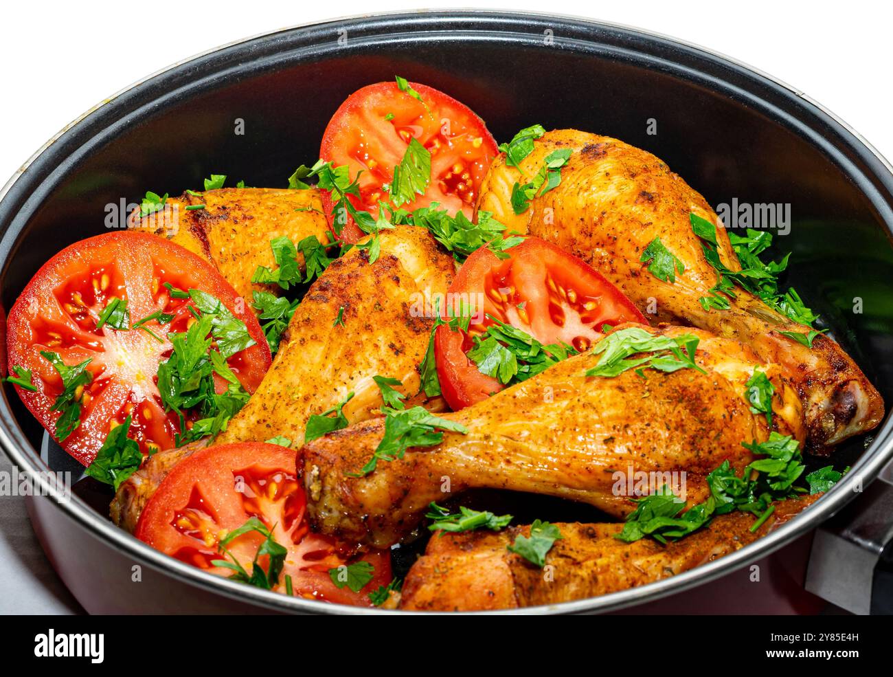 Cosce di pollo al forno dorate con pomodori e prezzemolo. Foto Stock