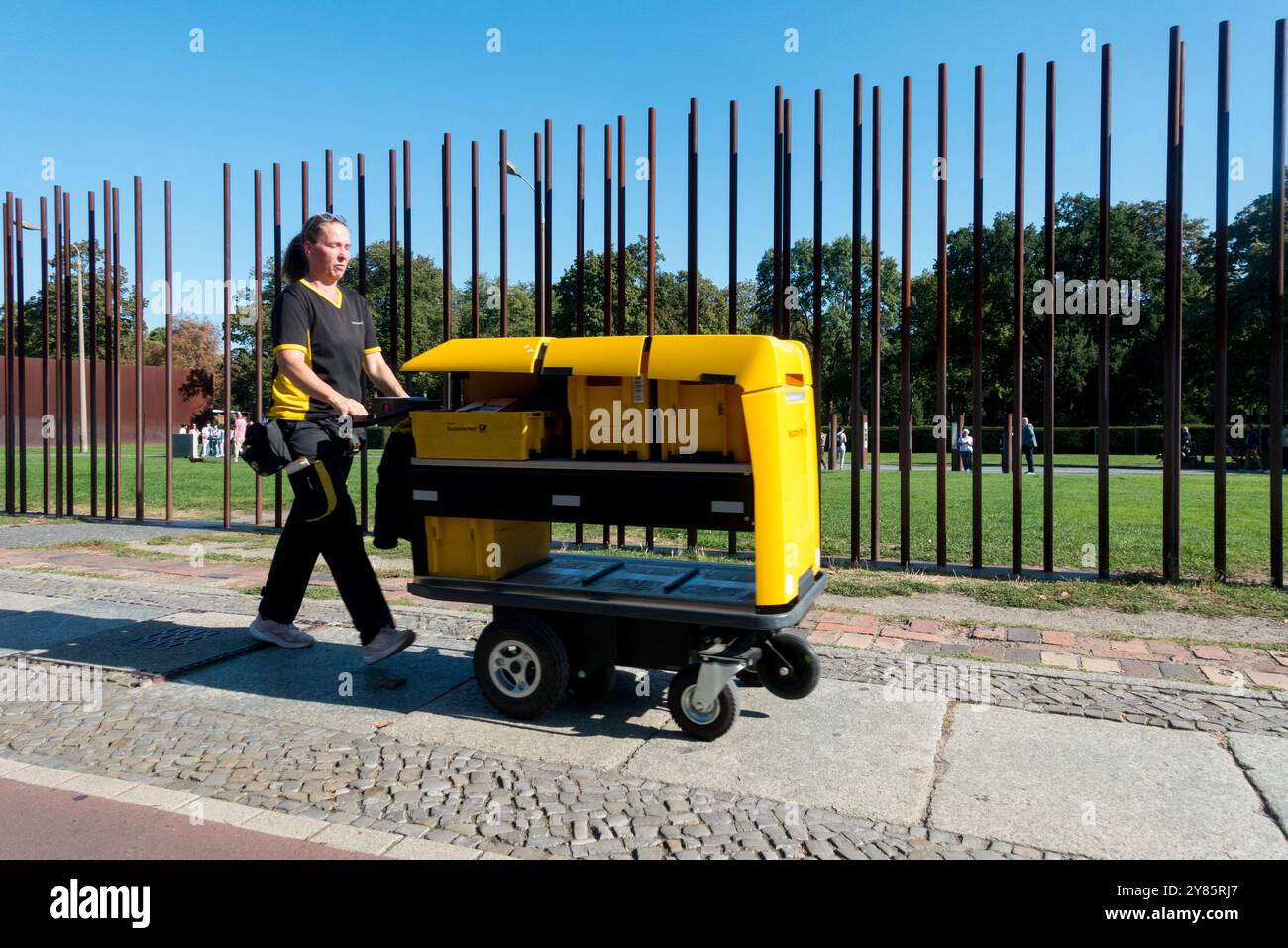 Ufficio Deutsche Post donna con carrello elettrico che cammina lungo il Memoriale del muro di Berlino Gedenkstätte Berliner Mauer Bernauer Straße Street Foto Stock