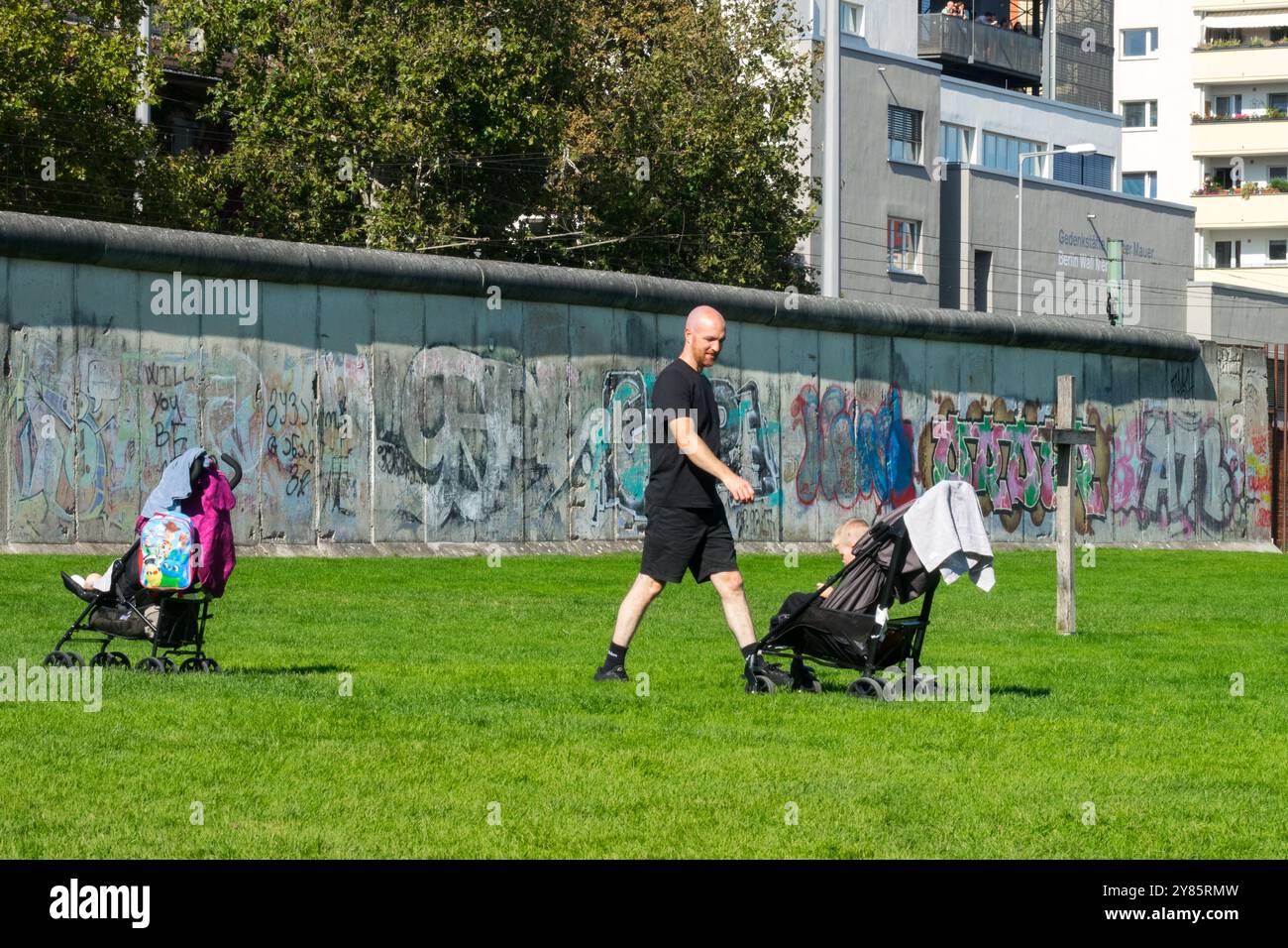 Uomo e bambino in Stroller Pram visita il Memoriale del muro di Berlino - Gedenkstätte Berliner Mauer Berlino Germania Europa via Bernauer Straße Foto Stock