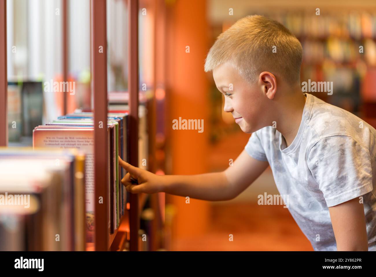 Intelligente bambino in età prescolare che sceglie libri nella biblioteca scolastica. Foto Stock