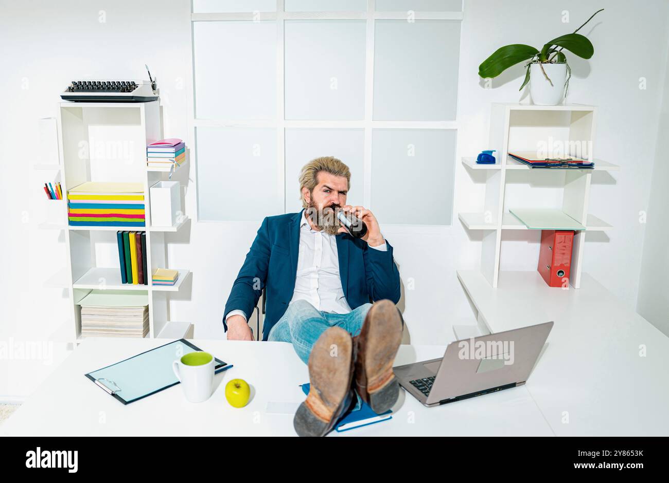 Hipster freelance, lavoratore d'ufficio, uomo d'affari che finiscono il lavoro prima della scadenza, ubriaco fine della giornata lavorativa. Un uomo d'affari ubriaco in ufficio. Foto Stock