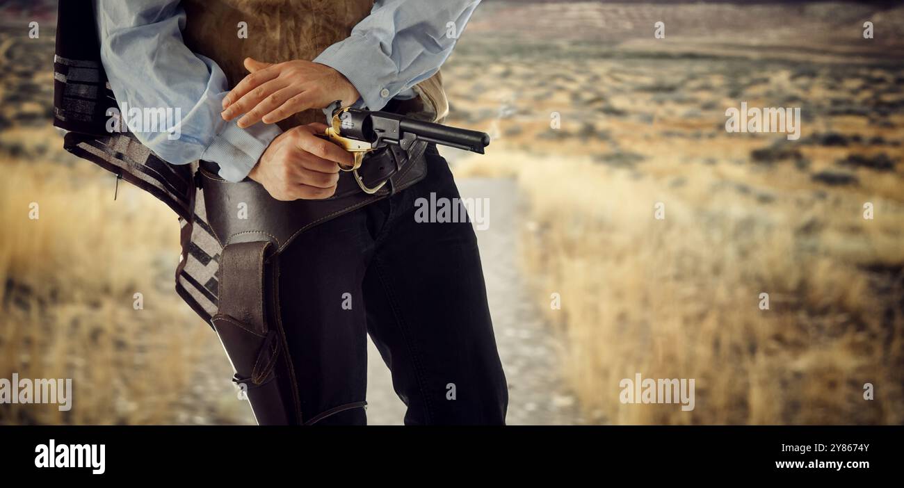 Il cowboy ruvido regola la sua pistola dopo aver sparato un colpo in un duello in stile western classico. In piedi in costume tradizionale pronto per il prossimo round dello sho Foto Stock