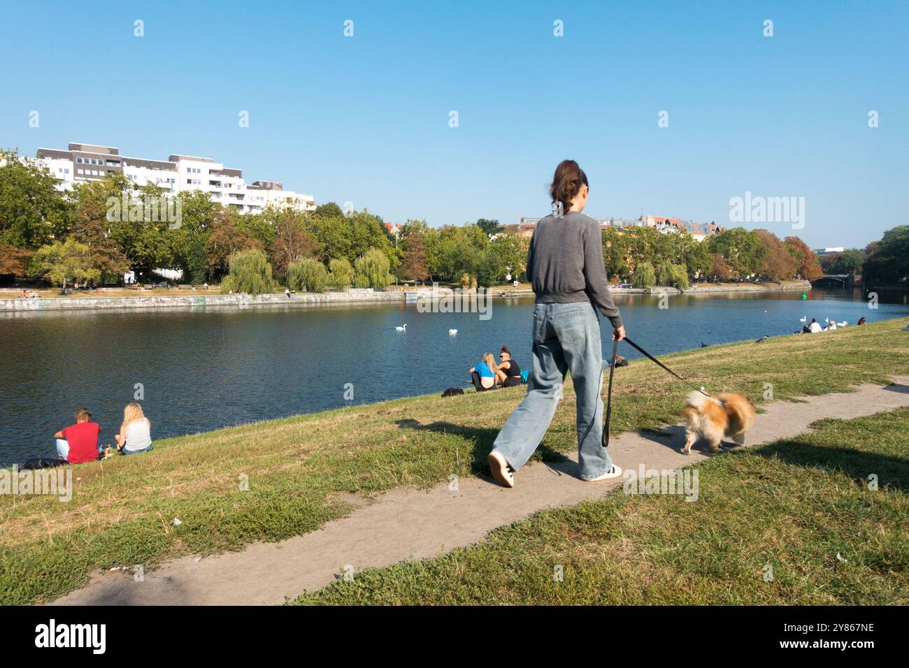 Giovane donna che cammina con il cane, Urbanhafen, Landwehrkanal, Kreuzberg, Berlino, canale del fiume Sprea in Germania Foto Stock