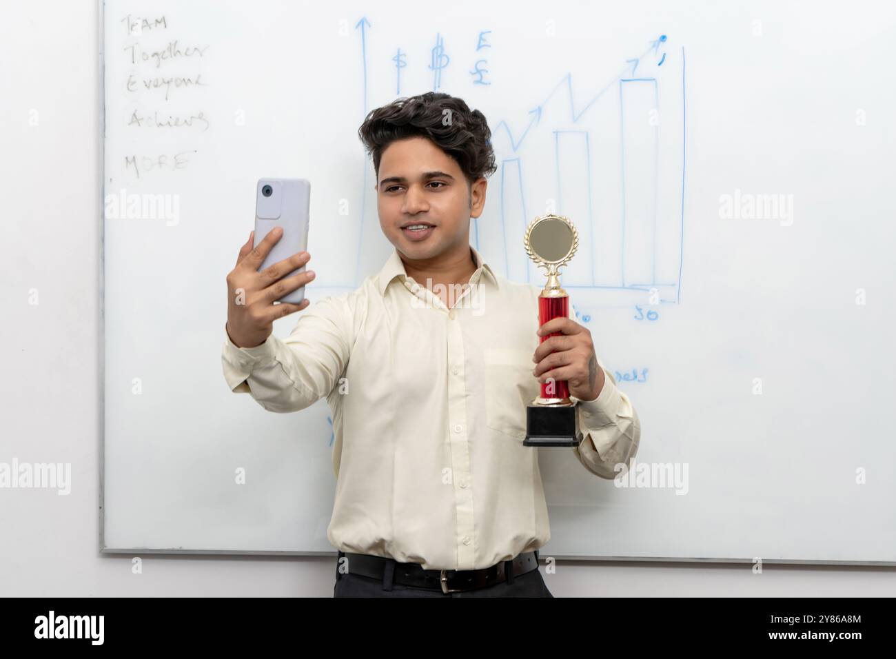 Un dipendente aziendale entusiasta celebra le sue prestazioni eccezionali potendo con un trofeo e scattando un selfie per catturare il momento del victo Foto Stock