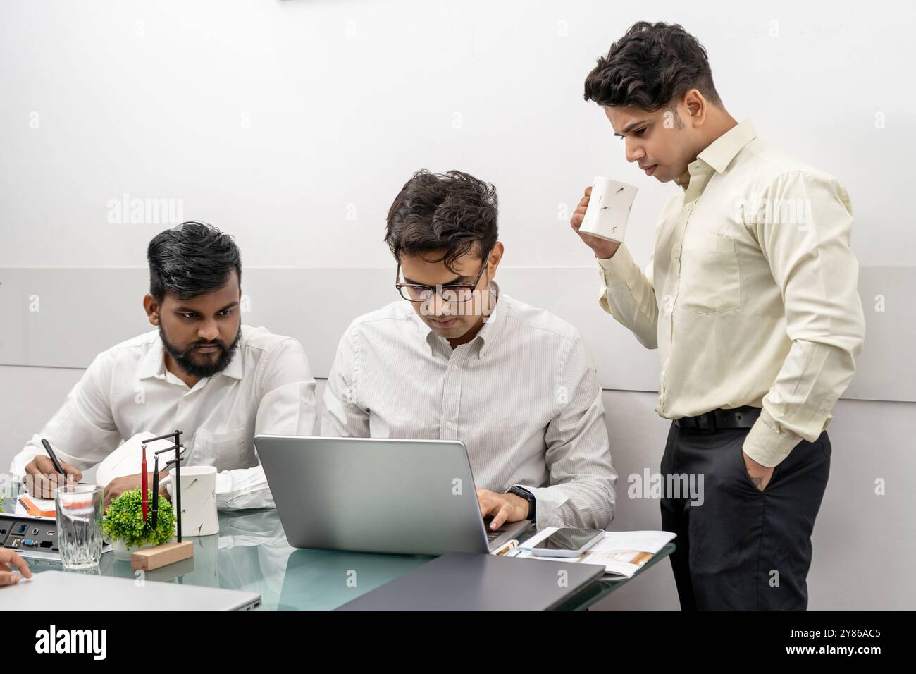 Un professionista IT altamente concentrato, esperto di tecnologia e ingegnere software lavora intensamente sul suo notebook, cercando di generare sol straordinari e innovativi Foto Stock