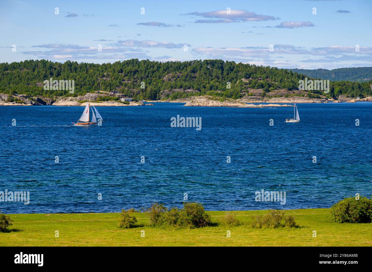 'Færder', un vecchio sloop pilota e una moderna barca a vela navigano nello stretto tra Jomfruland e le isole vicine. Telemark, Norvegia. Foto Stock