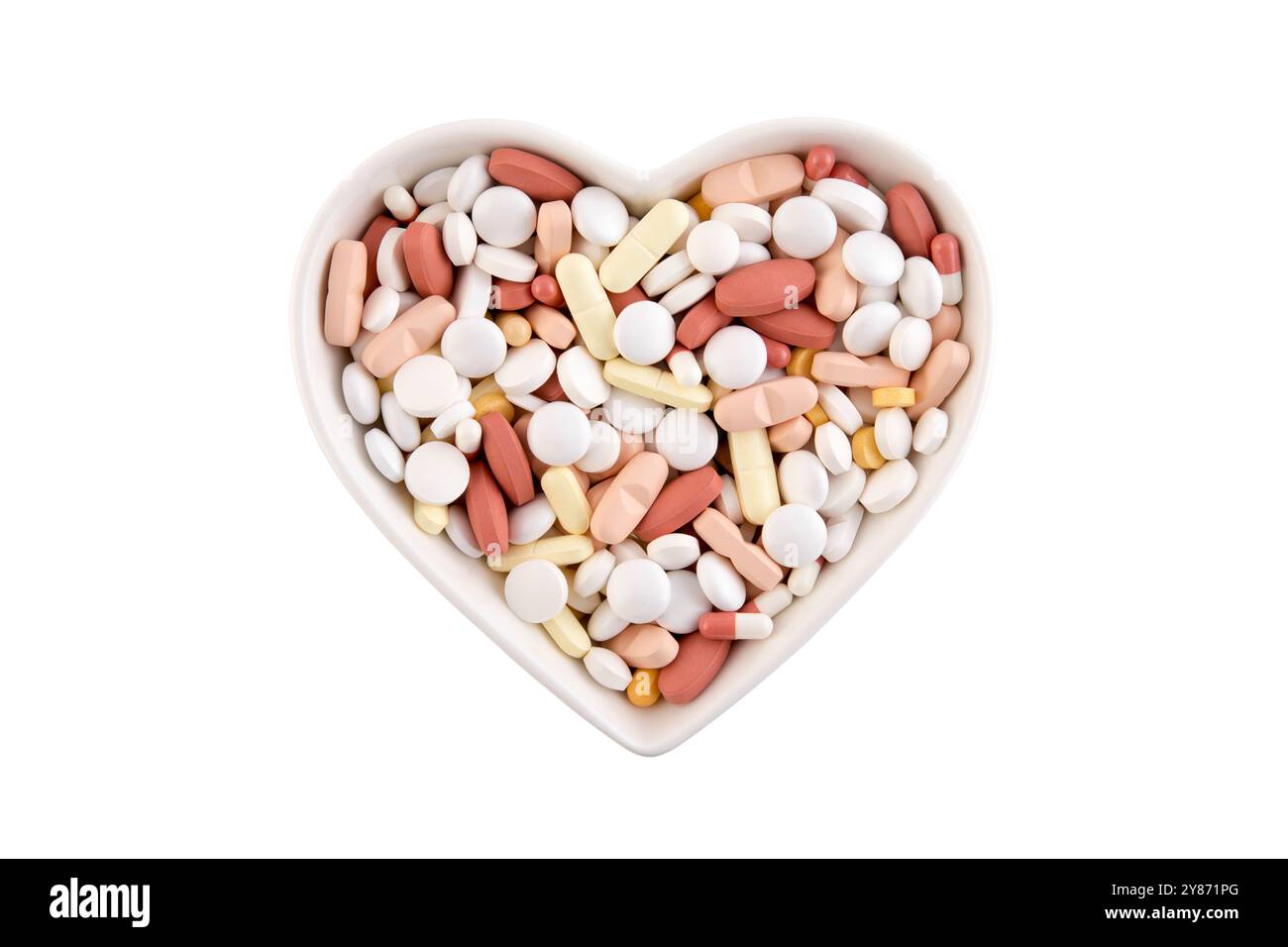 Piastra a forma di cuore con un mucchio di pillole medicinali o integratori alimentari isolati su sfondo bianco Foto Stock