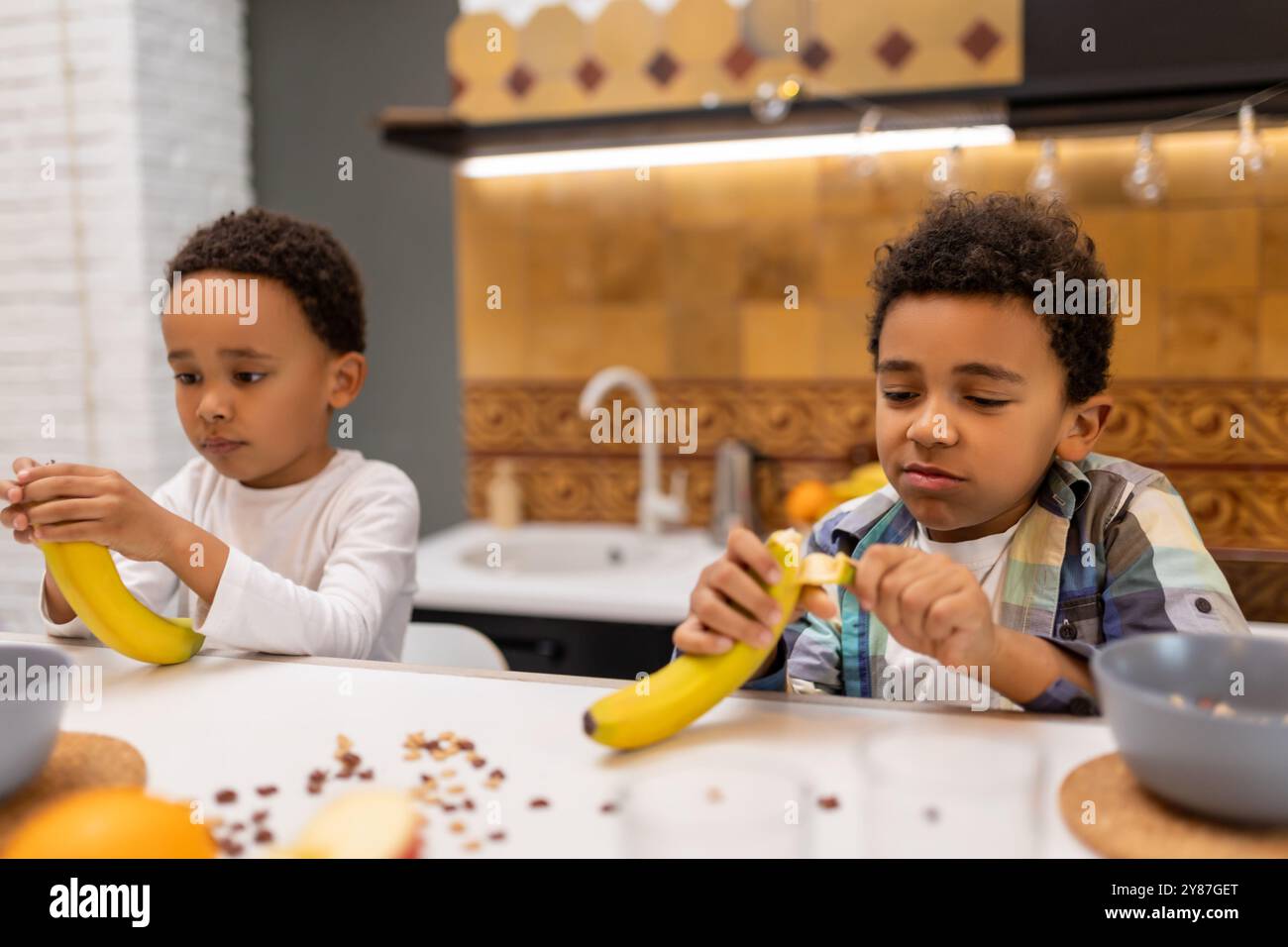 Due fratelli seduti al tavolo e a fare colazione Foto Stock