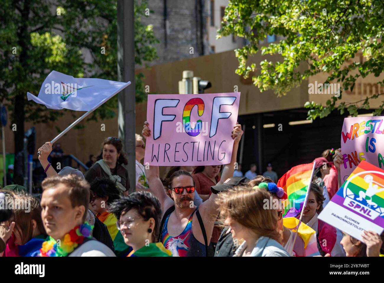 Uomo con un cartello rosa FCF Wrestling alla parata Helsinki Pride 2024 su Mannerheimintie a Helsinki, Finlandia Foto Stock