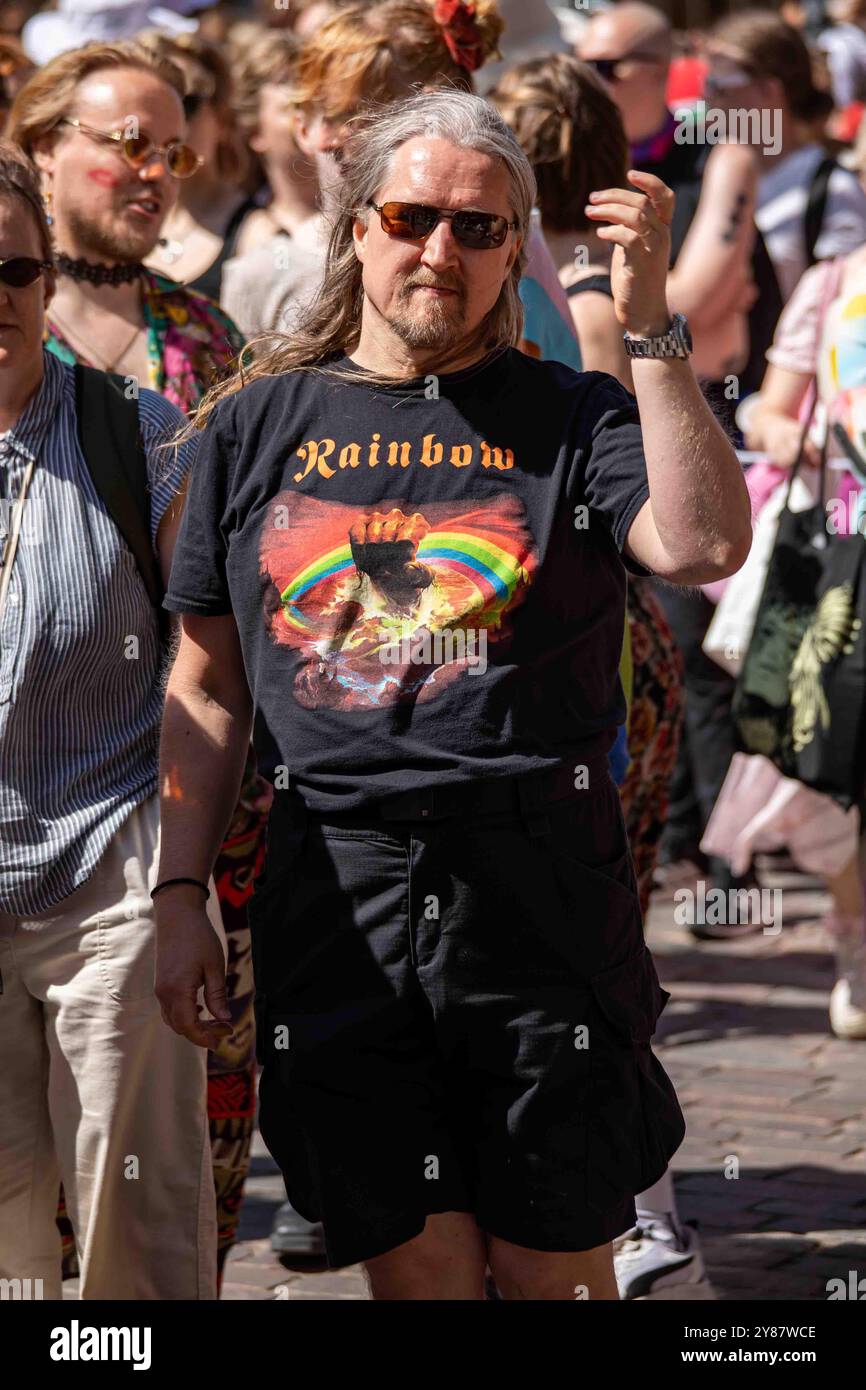 Longhaired man in a Rainbow, la band, T-shirt all'Helsinki Pride 2024 Parade on Mannerheimintie a Helsinki, Finlandia Foto Stock