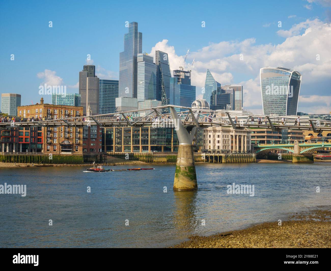 Il Millennium Bridge di Londra attraversa il Tamigi con lo skyline della City of London di alti edifici per uffici e grattacieli, Regno Unito Foto Stock