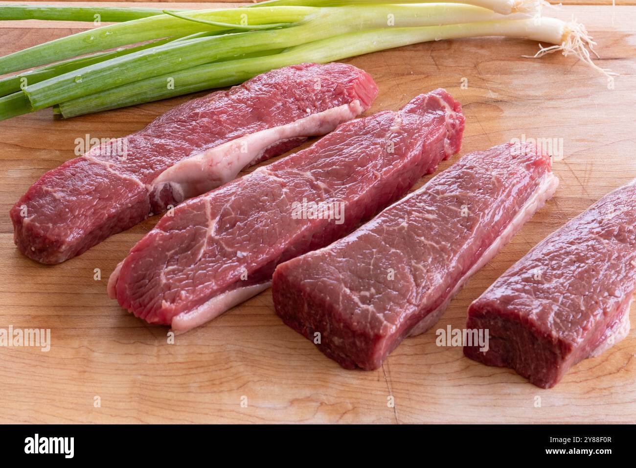 pezzi di bistecca di manzo cruda su un tagliere Foto Stock