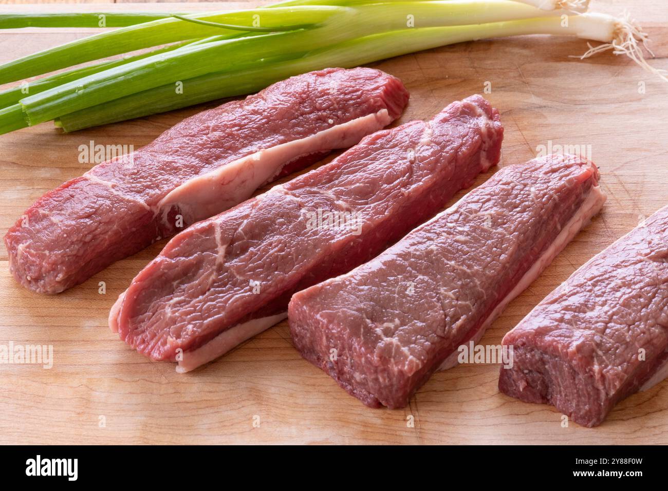 pezzi di bistecca di manzo cruda su un tagliere Foto Stock
