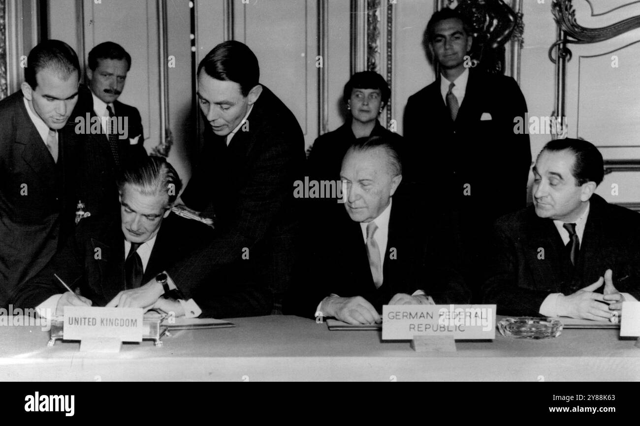 Eden Signs -- il ministro degli Esteri britannico Anthony Eden aggiunge la sua firma a un documento di accordo firmato da tutti e nove i delegati alla conclusione positiva dei colloqui delle nove potenze a Londra, oggi 3 ottobre. In particolare, il cancelliere della Germania Ovest Konrad Adenauer (seduto al centro) e il Premier francese Pierre Mendes - Franch (seduto a destra). 3 ottobre 1954. (Foto di Associated Press Photo) Foto Stock