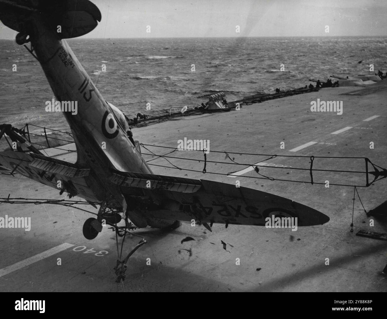 La camera catturò questo incidente aereo - Un Seafire Hits the Deck -- Un momento grafico caughter del cameraman a bordo della portaerei britannica Illustrious. Un fuoco di mare di uno squadrone della Royal Naval Volunteer Reserve atterrando sulla portaerei si ribaltò sul suo naso mentre colpiva la barriera. I pezzi dell'aereo possono essere visti volando alla fine, la ruota si fibbia all'indietro quando l'aereo colpisce il ponte. Le mani del ponte di volo cominciarono in avanti dai pozzi di cannone, ma il pilota, che può essere visto in cabina di pilotaggio, salì indenne. 10 settembre 1950. Foto Stock