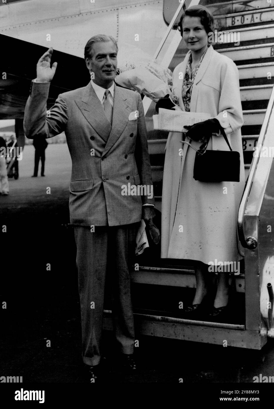 Edens in luna di miele -- il ministro degli Esteri Anthony Eden ondeggia come con sua moglie di un giorno, lascia l'aeroporto di Londra per la luna di miele in Portogallo Eden è l'ex 32enne Miss Clarissa Spencer Churchill. Si sono sposati a Londra ieri. 15 agosto 1952. Foto Stock
