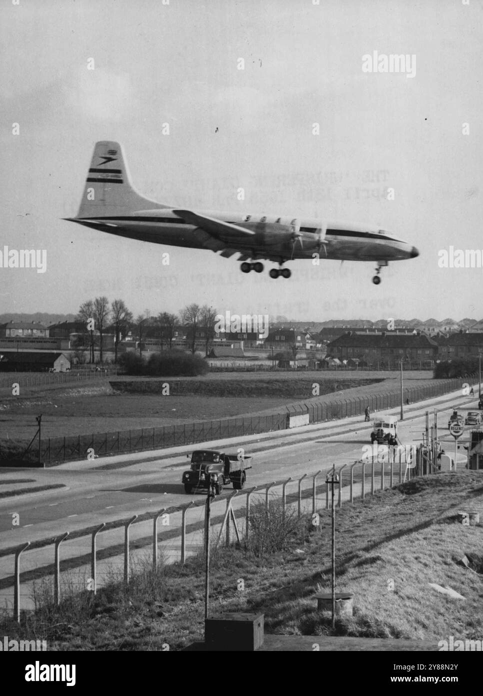 Il "gigante sussurrante" torna a casa -- oltre il traffico sulla strada principale di Gloucester, il Bristol Britannia arriva per atterrare al suo aeroporto di origine, Filton, Bristol, a ore giornaliere 55 minuti da Khartoum dopo le sue prove tropicali in Africa. Oltremare, Britannia era stata battezzata "il gigante sussurrante" - un tributo alla sua fuga silenziosa. Durante il viaggio di ritorno, l'aereo di linea ha combattuto 50 nodi di vento in testa per tutto il tragitto. Signore ***** Presidente di BOAC, che ***** Gli aerei della Britannia hanno inviato **** sugli aerei di linea ***** . 13 aprile 1955. (Foto di Reuterphoto). Foto Stock